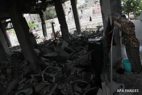 A Palestinian woman hangs laundry at her house, which was damaged during the recent Israeli war, in Rafah in the southern Gaza strip, on May 23, 2015. Photo by Abed Rahim Khatib