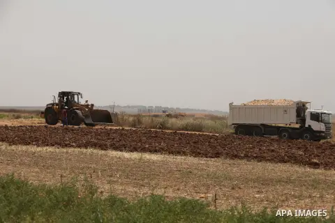 Palestinian workers use a bulldozer to build a street near the border with Israel, in Gaza City, on May 23, 2015. Photo by Ashraf Amra