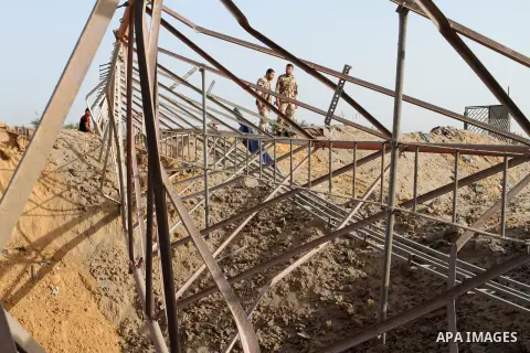 Palestinian security men look at a crater on the ground following an Israeli airstrike in the southern Gaza Strip near the town, of Rafah on May 27,2015. The Israeli air force carried out four strikes on militant targets...