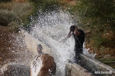Palestinians slide in a water canal used for irrigation to cool off as temperatures soar in the West Bank city of Jericho to 44 degrees Celsius (111 Fahrenheit), on May 27, 2015. Photo by Shadi Hatem