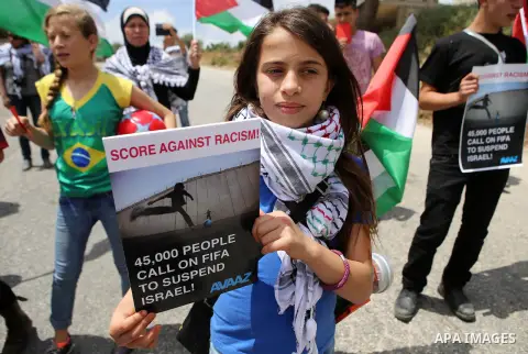 Palestinian activists hold banners and red cards in front of Israeli security forces during a demonstration against the Israeli Football Federation, in the West Bank village of Nabi Saleh, near Ramallah, 29 May 2015. The...