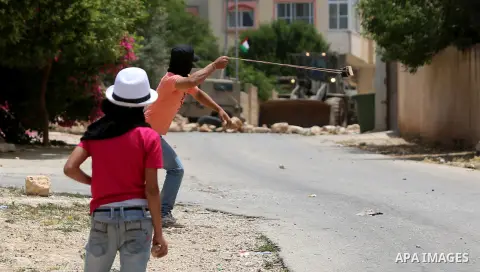 A Palestinian protester throws stones at Israeli security forces during clashes following a demonstration against the expropriation of Palestinian land by Israel in the West Bank village of Kfar Qaddum, near Nablus, on M...