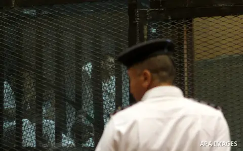 Egyptian defendants sit behind bars during their trial over a 2012 stadium riot in the canal city of Port Said that left 74 people dead on May 30, 2015 at the police academy in Cairo. The Egyptian court postponed its ver...