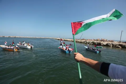 Palestinians hold flags as they ride a boat during a rally marking the 5th anniversary of the Mavi Marmara Gaza flotilla incident, at the seaport of Gaza City May 31, 2015. Nine activists, eight Turkish and one Turkish-A...