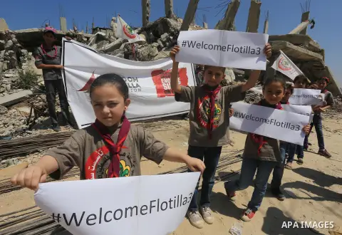 Palestinian children hold banners during a rally in front of the houses, which were damaged during the recent Israeli war, in Shejaiya neighborhood in Gaza city, on May 31, 2015. The first ship taking part in Freedom Flo...