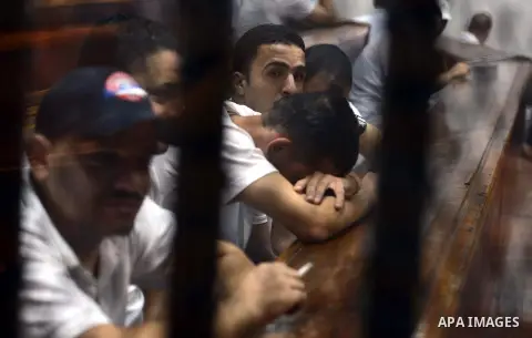 Egyptian defendants sit behind bars during their trial over a 2012 stadium riot in the canal city of Port Said that left 74 people dead on May 31, 2015 at the police academy in Cairo. The Egyptian court postponed its ver...