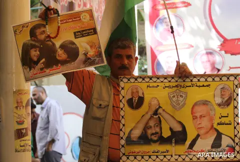 Palestinians hold pictures of prisoners held in Israeli jails, during a protest, in front of Red cross office, in Gaza city, on June 01, 2015. Photo by Mohammed Asad