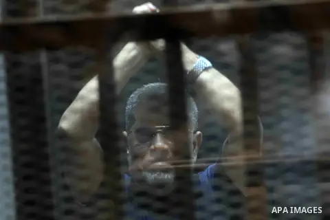 Ousted Egyptian president Mohamed Morsi gestures from the defendants cage as he attends his trial at the police academy on the outskirts of the capital Cairo on June 2, 2015. The Egyptian court postponed its final ruling...