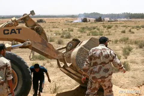 Palestinian militants of the Ezzedine al-Qassam Brigades, Hamas' armed wing, stand near a Palestinian bulldozer as they watch an Israeli bulldozers working along a barbed wire fence that separates Rafah in the southern G...