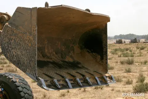 Palestinians rid a bulldozer in front of Israeli bulldozers working along a barbed wire fence that separates Rafah in the southern Gaza Strip and the Israeli border, on June 03, 2015. Israeli troops backed by military ve...