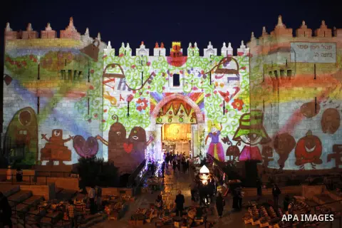 People watch an audiovisual light show projected over the ancient walls of Jerusalem's Damascus Gate in the old city during the Festival of Lights, on June 4, 2015. The festival is an annual event where thousands take pa...