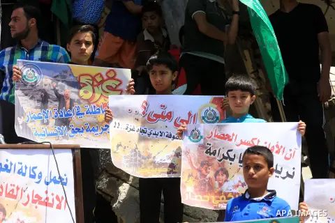 Palestinian children hold placards during a protest against the United Nations Relief and Works Agency (UNRWA) and the unity government, and calling for an acceleration in the reconstruction of homes destroyed during a 5...