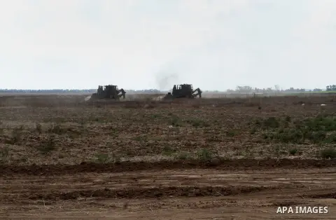 Israeli bulldozers work along a barbed wire fence that separates Khan Yunis in the southern Gaza Strip and the Israeli border, on June 10, 2015. Israel is to reopen border crossings to and from the Gaza Strip the coming...