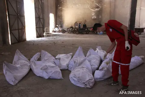 A Red Crescent worker inspects the bodies of dead fighters loyal to Syrian President Bashar al-Assad during an exchange of dead bodies between Free Syrian Army and Syrian Government forces, in Bustan al-Qasr district in...
