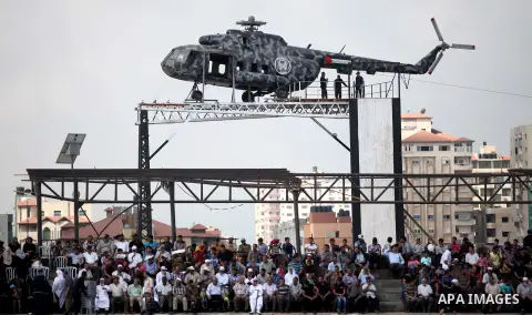 Spectators watch on as members of the Palestinian Hamas security forces take part in a graduation ceremony in Gaza City on June 16, 2015, in front of a recently installed statue of a renovated helicopter belonging to lat...