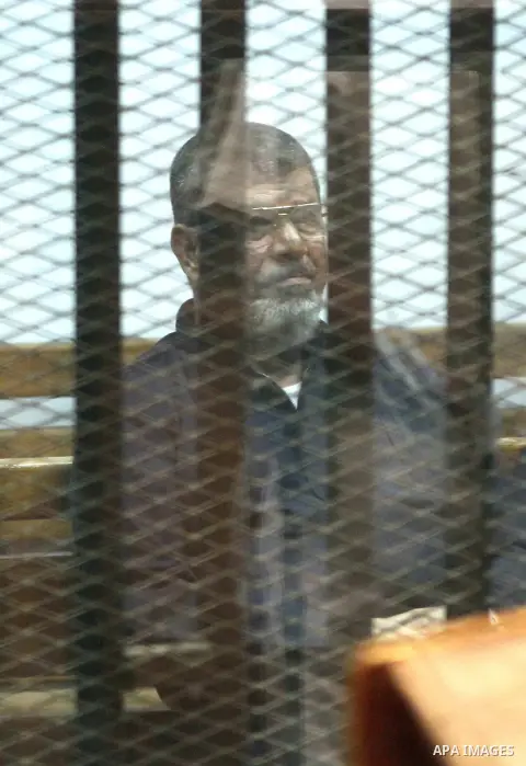 Egypt's ousted Islamist president Mohamed Morsi stands behind the bars during his trial in Cairo on June 16, 2015. An Egyptian court upheld a death sentence against Morsi for plotting jailbreaks and attacks on police dur...