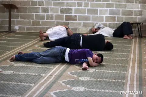 Palestinians rest as others pray and read the Koran in a mosque during the holy month of Ramadan in Gaza city on 18 June 2015. Muslims around the world are observing the holy fasting month of Ramadan in which they refrai...