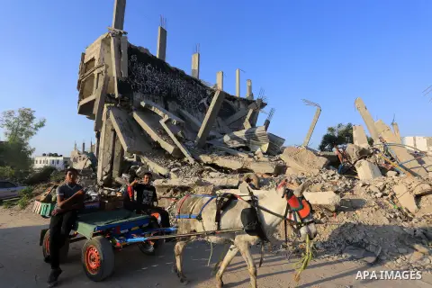 Palestinians ride a donkey cart in front of the remains of houses, which were destroyed during the 50-day Israeli war in the summer of 2014, on the second day of the holy month of Ramadan, in Gaza city on June 19, 2015....