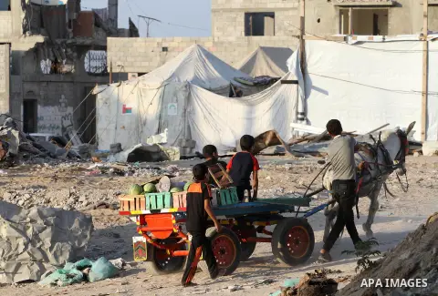 Palestinians ride a donkey cart in front of the remains of houses, which were destroyed during the 50-day Israeli war in the summer of 2014, on the second day of the holy month of Ramadan, in Gaza city on June 19, 2015....