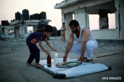 A Palestinian man prepares to break his fast on the remains of his house, which was destroyed during the 50-day Israeli war in the summer of 2014, on the second day of the holy month of Ramadan, in Beit Lahia in the nort...