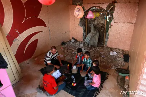 Members of a Palestinian family break their fast on the remains of their house, which was destroyed during the 50-day Israeli war in the summer of 2014, on the holy month of Ramadan, in KhanYounis in the southern Gaza St...