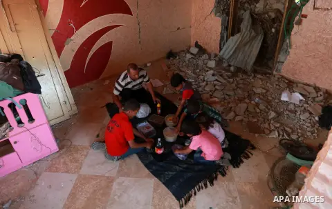 Members of a Palestinian family break their fast on the remains of their house, which was destroyed during the 50-day Israeli war in the summer of 2014, on the holy month of Ramadan, in KhanYounis in the southern Gaza St...