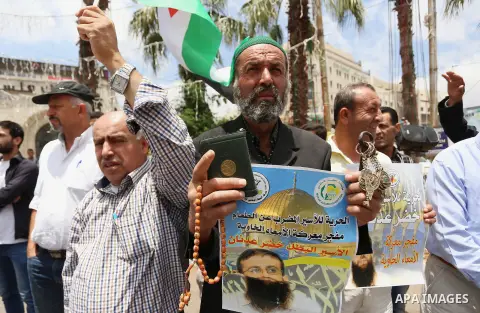 Palestinians hold placard during a protest in support of Palestinian Khader Adnan, a senior member of the Islamic Jihad who was jailed in Israel without a trial, in the West Bank city of Ramallah on June 25, 2015. Photo...