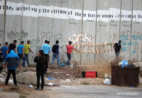 Palestinians, not permitted by Israeli security forces to cross into Jerusalem from the West Bank due to an age limit, use a ladder to climb over a section of the controversial Israeli barrier as they try to make their w...