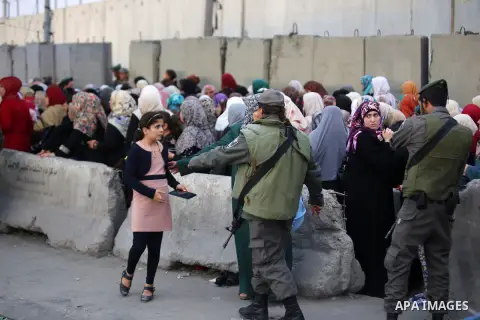 Israeli border police stand guard as Palestinians wait to show their identity cards to Israeli security officers to make their way to attend the second Friday prayer of Ramadan in Jerusalem's al-Aqsa mosque, at Qalandia...
