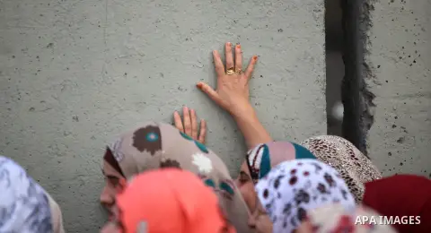 Palestinian women walk next to the controversial Israeli barrier to make their way to attend the second Friday prayer of Ramadan in Jerusalem's al-Aqsa mosque, at Qalandia checkpoint near the West Bank city of Ramallah J...
