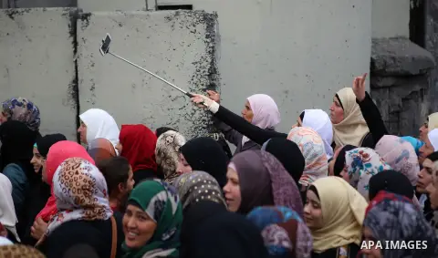 Palestinian women walk next to the controversial Israeli barrier to make their way to attend the second Friday prayer of Ramadan in Jerusalem's al-Aqsa mosque, at Qalandia checkpoint near the West Bank city of Ramallah J...