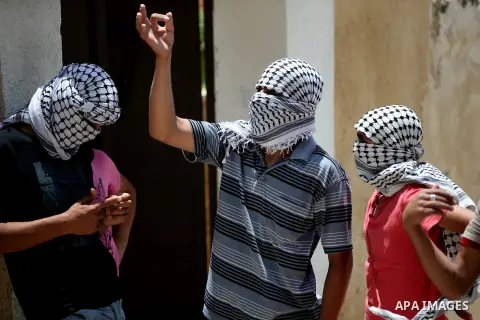 Masked Palestinian protesters look on during clashes with Israeli security forces following a demonstration against the expropriation of Palestinian land by Israel in the West Bank village of Kfar Qaddum, near Nablus, on...