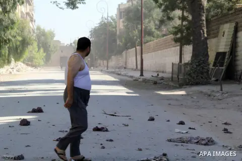 A Syrian man walks in an a street after a reported bomb barrel attack by Syrian government forces in Jub al-Qubbah neighborhood in the northern Syrian city of Aleppo, June 26, 2015. Photo by Ameer al-Halbi