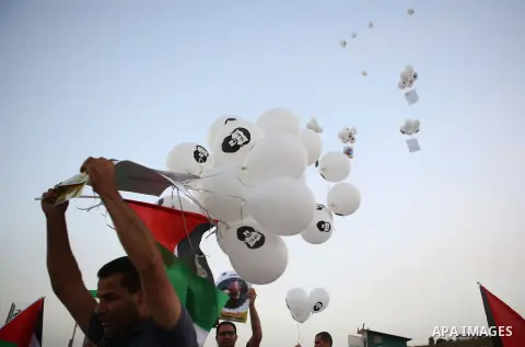 Palestinian protesters hold balloons and posters of prisoners during a protest demanding for their release from Israeli jails, outside Ofer Israeli military prison, near the West Bank city of Ramallah on June 27, 2015. P...