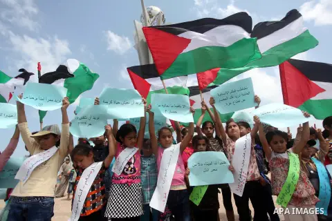 Palestinians children hold placards and wave their national flag during a rally to show support for activists aboard a flotilla of boats who are soon to set sail for Gaza in a fresh bid to break Israel's blockade of the...