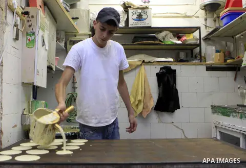 A Palestinian man prepares traditional pancakes known as ''Qatayef'' on the holy month of Ramadan, in Jerusalem's old city on June 29, 2015. During Ramadan, Muslim believers abstain from eating, drinking, smoking and hav...