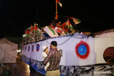Palestinian activists sit on a model of a ship during a rally in solidarity with activists aboard a flotilla of boats who are soon to set sail for Gaza in a fresh bid to break Israel's blockade of the territory, in the W...