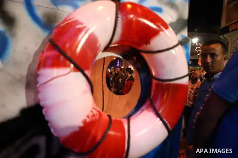 Palestinian activists sit on a model of a ship during a rally in solidarity with activists aboard a flotilla of boats who are soon to set sail for Gaza in a fresh bid to break Israel's blockade of the territory, in the W...