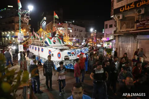 Palestinians walk next to a model of a ship during a rally in solidarity with activists aboard a flotilla of boats who are soon to set sail for Gaza in a fresh bid to break Israel's blockade of the territory, in the West...