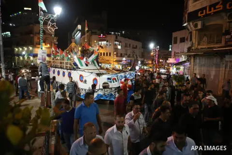 Palestinians walk next to a model of a ship during a rally in solidarity with activists aboard a flotilla of boats who are soon to set sail for Gaza in a fresh bid to break Israel's blockade of the territory, in the West...
