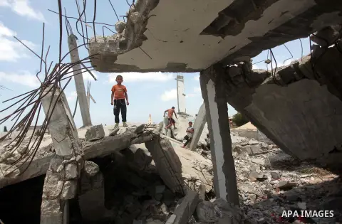 Palestinian childern stand on the ruins of houses, that witnesses said were destroyed by Israeli shelling during a 50-day war last summer, in Khan Younis in the southern Gaza Strip July 2, 2015. Robert Turner has no quic...