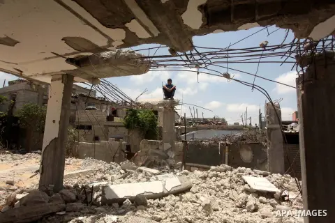 A Palestinian boy sits on the ruins of houses, that witnesses said were destroyed by Israeli shelling during a 50-day war last summer, in Khan Younis in the southern Gaza Strip July 2, 2015. Robert Turner has no quick an...