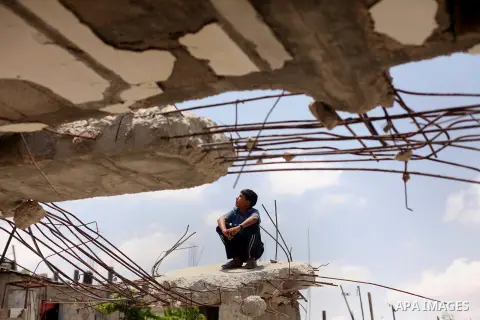 A Palestinian boy sits on the ruins of houses, that witnesses said were destroyed by Israeli shelling during a 50-day war last summer, in Khan Younis in the southern Gaza Strip July 2, 2015. Robert Turner has no quick an...