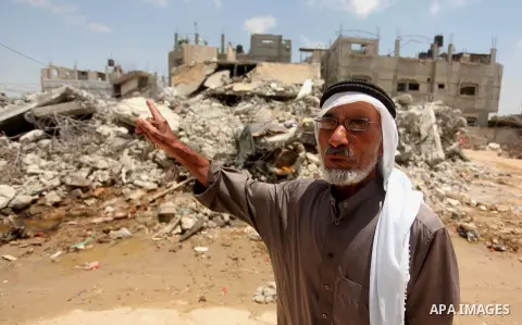 A Palestinian man looks on as she stands in front of the ruins of his house, that witnesses said was destroyed by Israeli shelling during a 50-day war last summer, in Khan Younis in the southern Gaza Strip July 2, 2015....