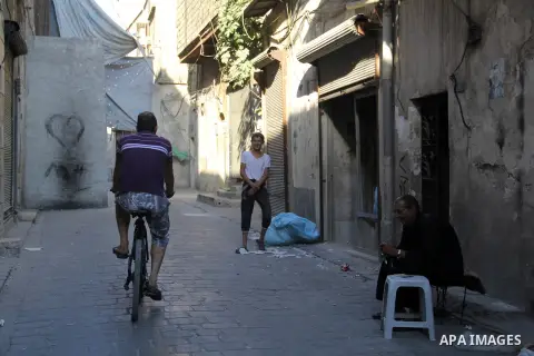 A Syrian man rides a bicycle at the street in the northern Syrian city of Aleppo on July 05, 2015. The Syrians used the wreckage Buses, cars and concrete slabs to protect themselves from the snipers of Syrian regime forc...