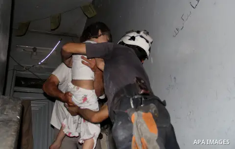 Syrian firefighters carry children following a reported bomb barrel attack by Syrian government forces at al-Salheen neighborhood in the northern Syrian city of Aleppo, July 12, 2015. Photo by Ameer al-Halbi