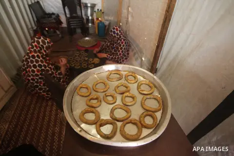 Palestinians, whose house was destroyed by what witnesses said was Israeli shelling during a 50-day war last summer, make traditional cake inside their makeshift shelter, ahead of Eid-al-Fitr celebrations in Khan Younis...