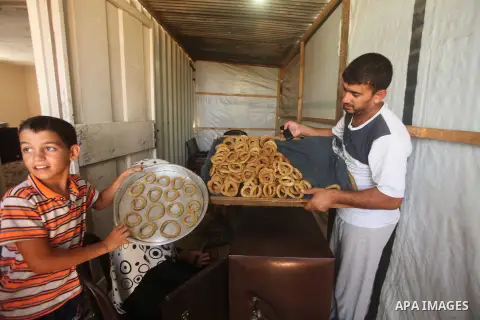 Palestinians, whose house was destroyed by what witnesses said was Israeli shelling during a 50-day war last summer, make traditional cake inside their makeshift shelter, ahead of Eid-al-Fitr celebrations in Khan Younis...