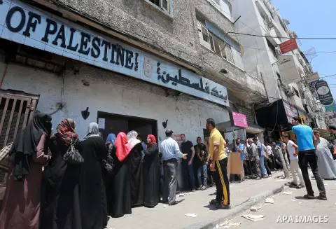Palestinians of Social Affairs wait in front of Bank of Palestine to withdrew their financial aid in Gaza City on July 15, 2015. Photo by Mohammed Asad
