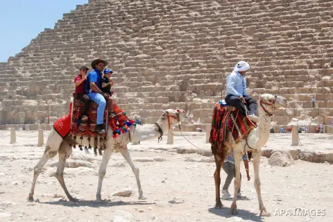 Egyptians ride a camel in front of the Giza pyramids, on the third day of Eid al-Fitr holiday which marks the end of the Muslim holy month of Ramadan, in Cairo on July 19, 2015. Photo by Amr Sayed